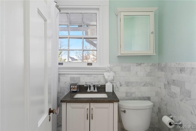 bathroom with vanity, tile walls, toilet, and wainscoting