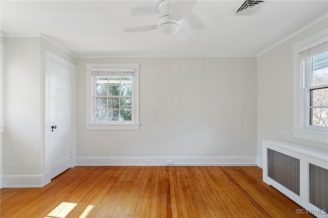 spare room with crown molding, baseboards, visible vents, and light wood finished floors