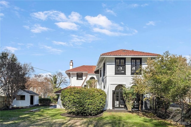 mediterranean / spanish home with a front yard, a balcony, fence, stucco siding, and a tile roof