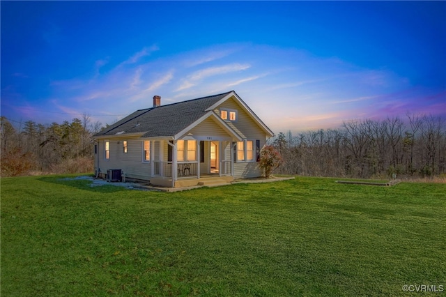 exterior space featuring central air condition unit, a chimney, a porch, and a lawn