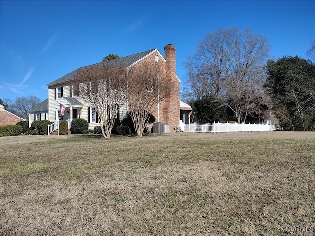 view of property exterior featuring central AC unit, a lawn, a chimney, and fence