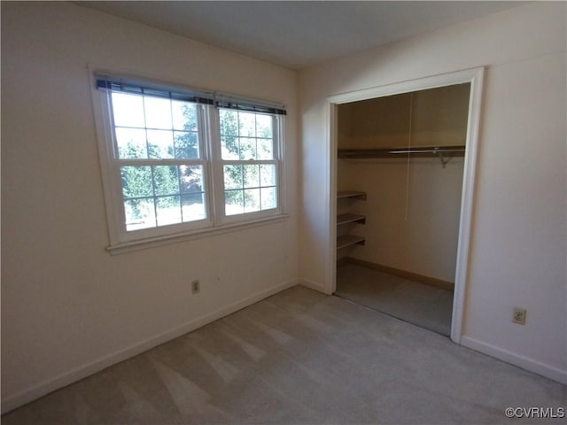 unfurnished bedroom featuring a closet, light carpet, and baseboards