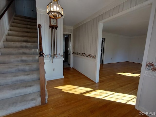 interior space featuring stairway, ornamental molding, wood finished floors, and an inviting chandelier