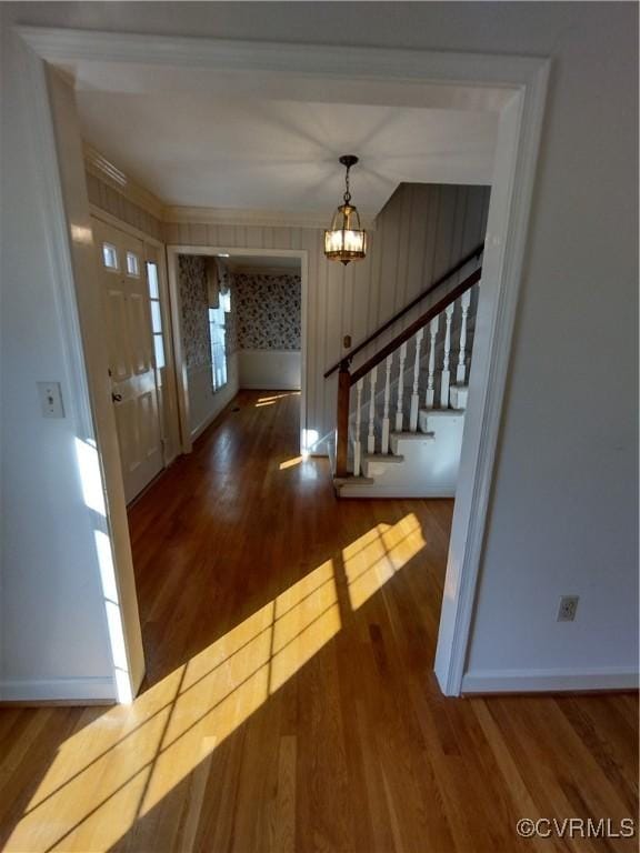 entryway with ornamental molding, wood finished floors, a chandelier, baseboards, and stairs