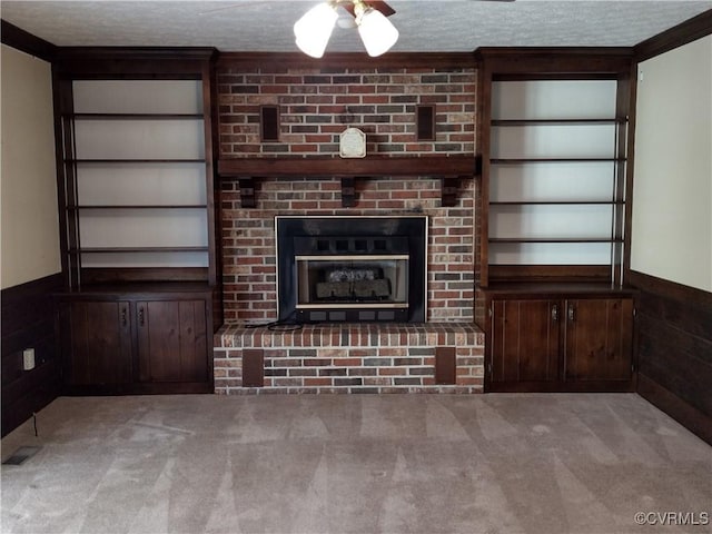 unfurnished living room featuring a wainscoted wall, carpet, and a textured ceiling