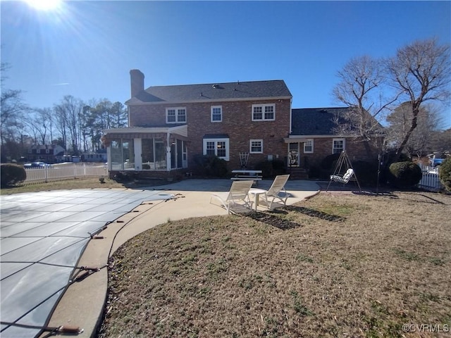 back of house featuring a fenced in pool, brick siding, a patio, a sunroom, and fence