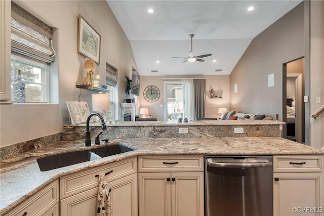 kitchen featuring stainless steel dishwasher, lofted ceiling, cream cabinets, and a sink