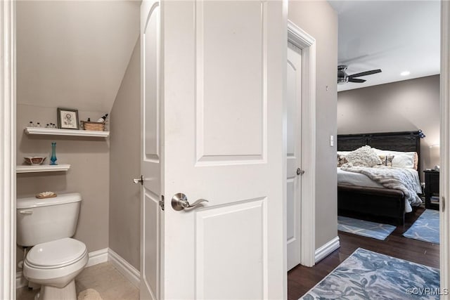 ensuite bathroom with connected bathroom, baseboards, toilet, wood finished floors, and a ceiling fan