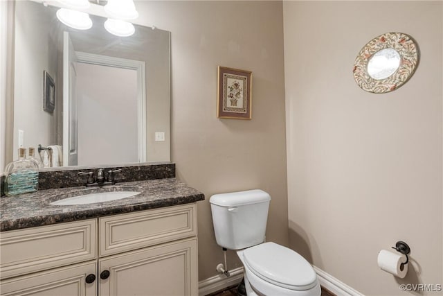 bathroom with vanity, toilet, and baseboards