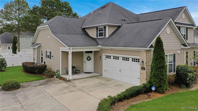 view of front of property featuring a front lawn, fence, a porch, concrete driveway, and a garage