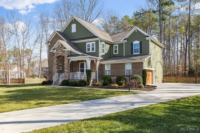 craftsman inspired home with driveway, a porch, fence, a front lawn, and board and batten siding