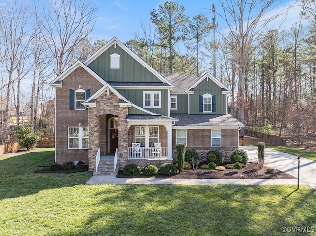 craftsman-style home with covered porch, a front lawn, board and batten siding, and brick siding