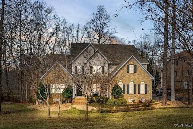 view of front of property with a chimney, a front lawn, and brick siding