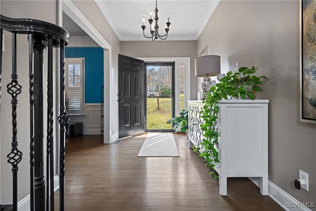 foyer with an inviting chandelier, ornamental molding, and dark wood finished floors