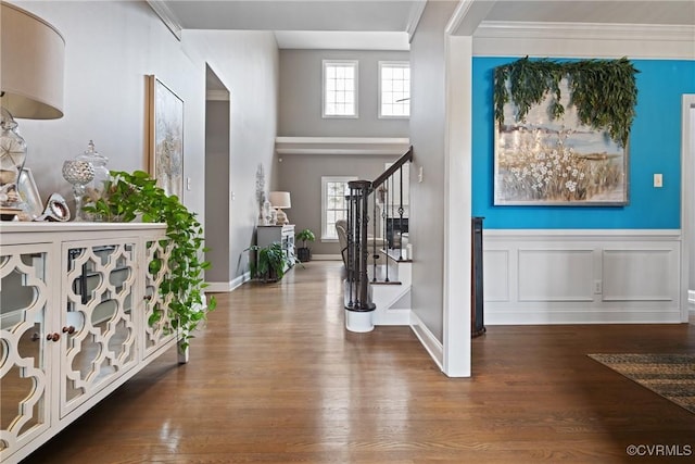 entrance foyer with stairs, ornamental molding, a decorative wall, and wood finished floors