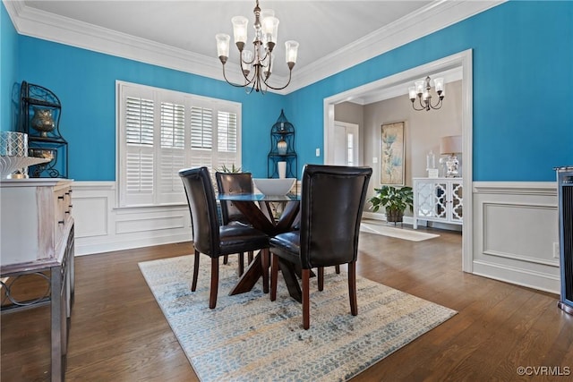 dining space with an inviting chandelier, dark wood finished floors, crown molding, and a wainscoted wall