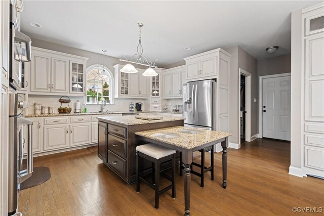 kitchen featuring stainless steel fridge, white cabinetry, and a center island