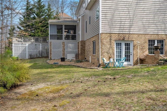 view of property exterior with a yard, brick siding, and a sunroom