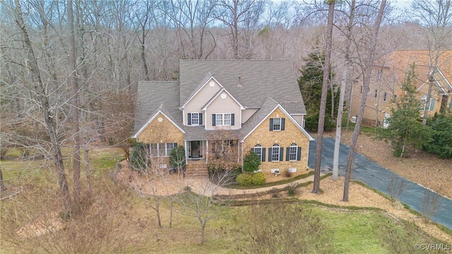 traditional-style home featuring roof with shingles, aphalt driveway, and brick siding