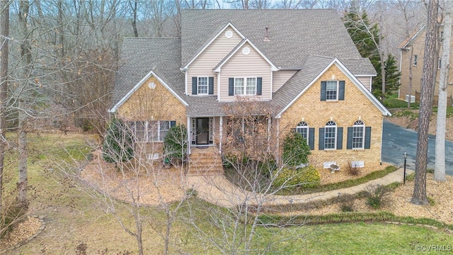 traditional home with a shingled roof and brick siding