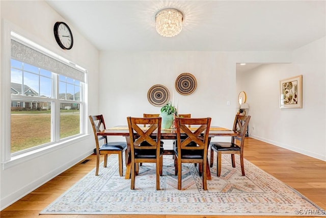 dining area with a notable chandelier, baseboards, and light wood-type flooring