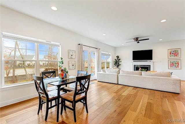 dining room with a high end fireplace, recessed lighting, and light wood finished floors