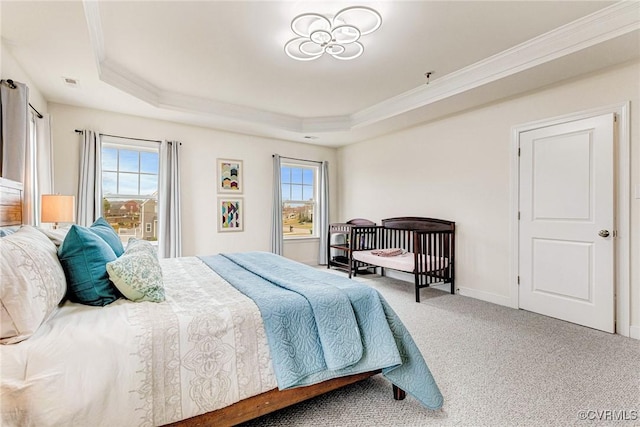 bedroom with a tray ceiling, carpet floors, and multiple windows