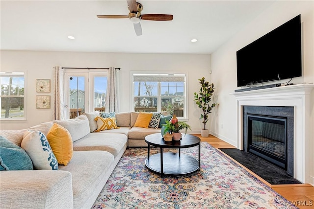 living room with wood finished floors, a ceiling fan, baseboards, a fireplace with flush hearth, and recessed lighting