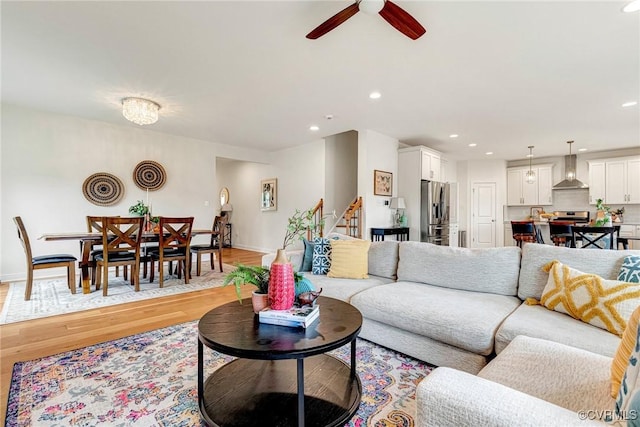 living room with light wood-style flooring, a ceiling fan, recessed lighting, stairway, and baseboards