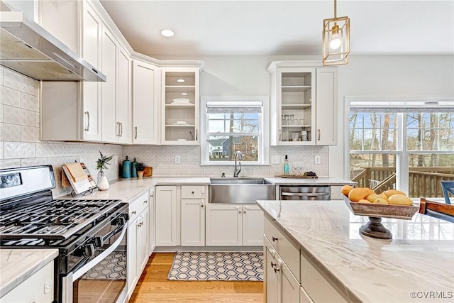 kitchen with a sink, tasteful backsplash, appliances with stainless steel finishes, wall chimney exhaust hood, and white cabinets