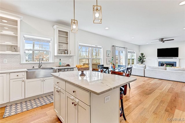 kitchen featuring light wood-type flooring, a breakfast bar, a sink, backsplash, and ceiling fan