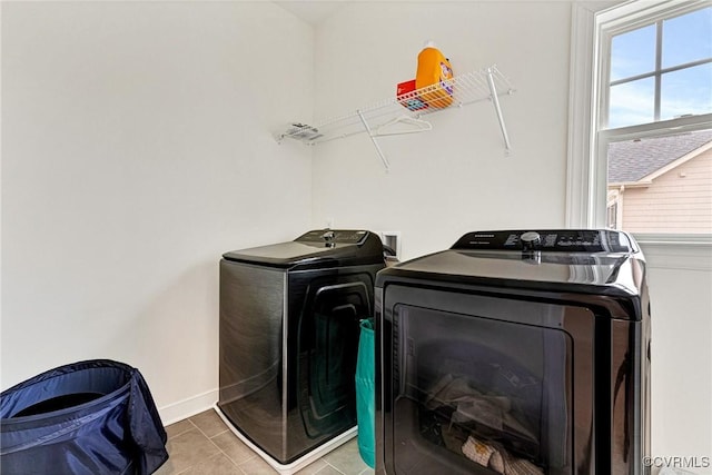 washroom with light tile patterned floors, baseboards, laundry area, and washing machine and clothes dryer