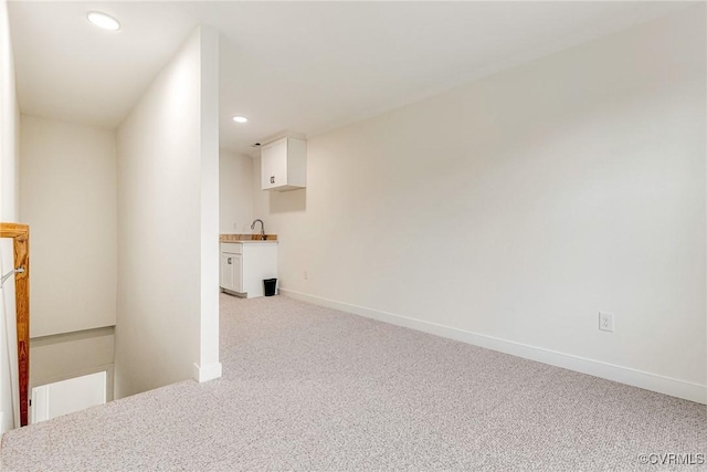 interior space with a sink, baseboards, light colored carpet, and recessed lighting