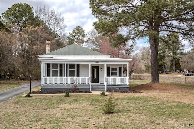 view of front of property with crawl space, a chimney, a porch, and a front yard