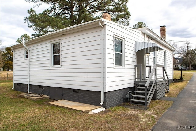 view of home's exterior featuring a yard, crawl space, and a chimney