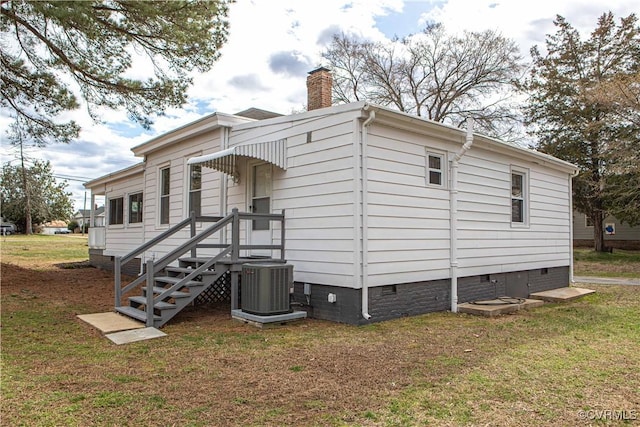 view of side of home featuring crawl space, central air condition unit, a chimney, and a lawn