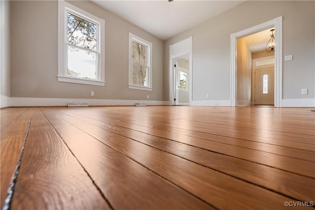 unfurnished room with hardwood / wood-style flooring, visible vents, and baseboards