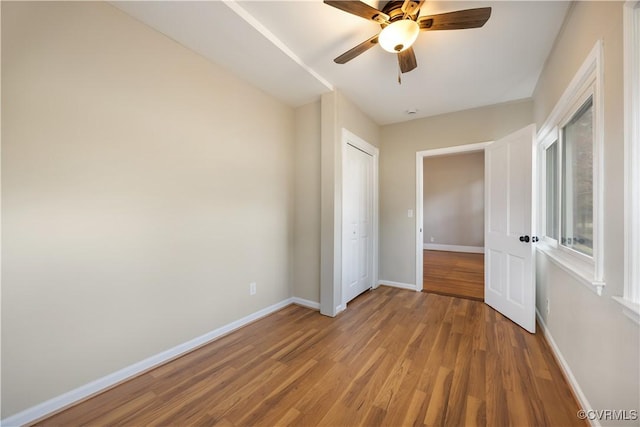 unfurnished bedroom with light wood-style floors, ceiling fan, baseboards, and a closet