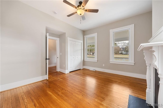 unfurnished bedroom featuring ceiling fan, visible vents, baseboards, a closet, and light wood finished floors