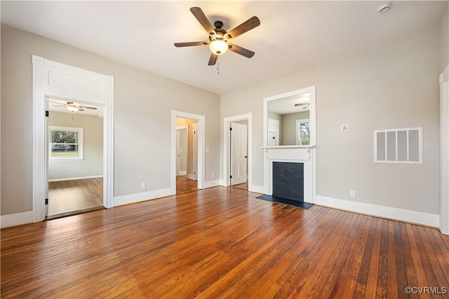 unfurnished living room featuring visible vents, baseboards, hardwood / wood-style flooring, a fireplace with flush hearth, and ceiling fan