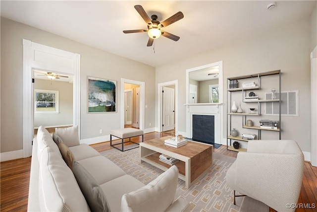 living room featuring plenty of natural light, a fireplace, wood finished floors, and baseboards