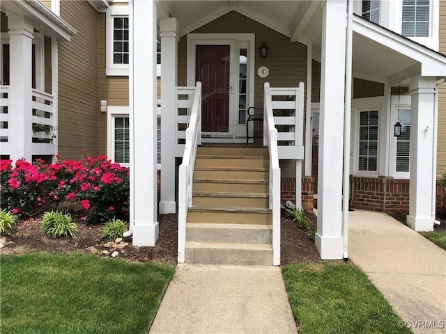 property entrance with covered porch and brick siding