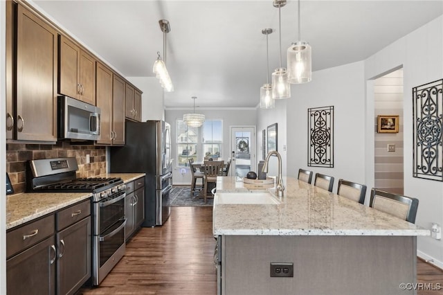 kitchen featuring stainless steel appliances, dark wood-style flooring, a sink, and decorative backsplash