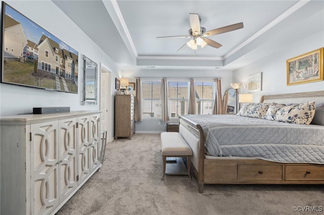 bedroom with ceiling fan, light colored carpet, baseboards, ornamental molding, and a tray ceiling