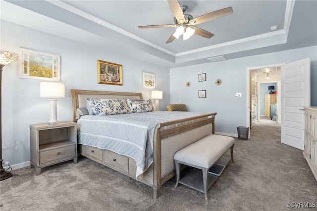 carpeted bedroom featuring ceiling fan, baseboards, ornamental molding, a tray ceiling, and attic access