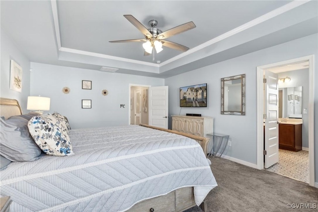 carpeted bedroom with baseboards, a raised ceiling, ensuite bath, ceiling fan, and ornamental molding