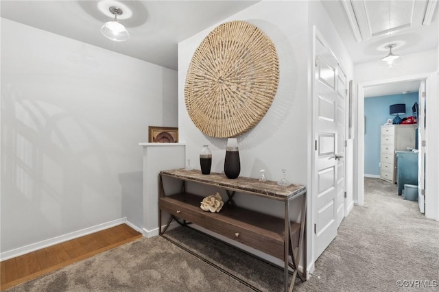 hall with carpet, attic access, and baseboards