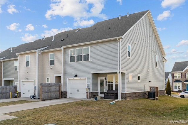 back of property featuring central air condition unit, a garage, fence, driveway, and a lawn