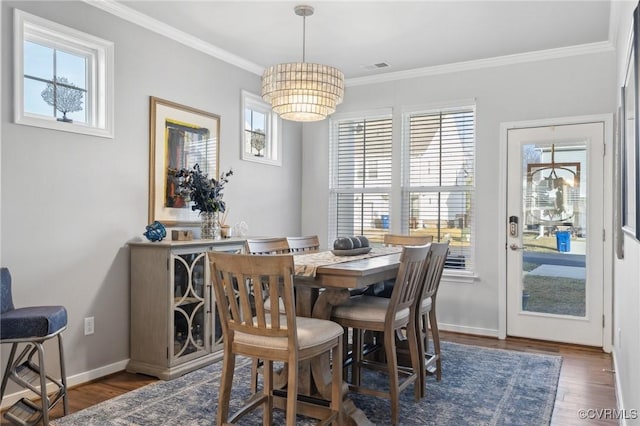 dining space featuring ornamental molding, wood finished floors, visible vents, and baseboards