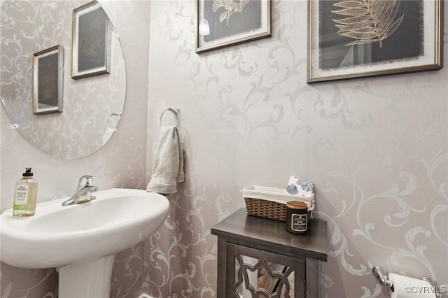 half bathroom with a sink and wallpapered walls